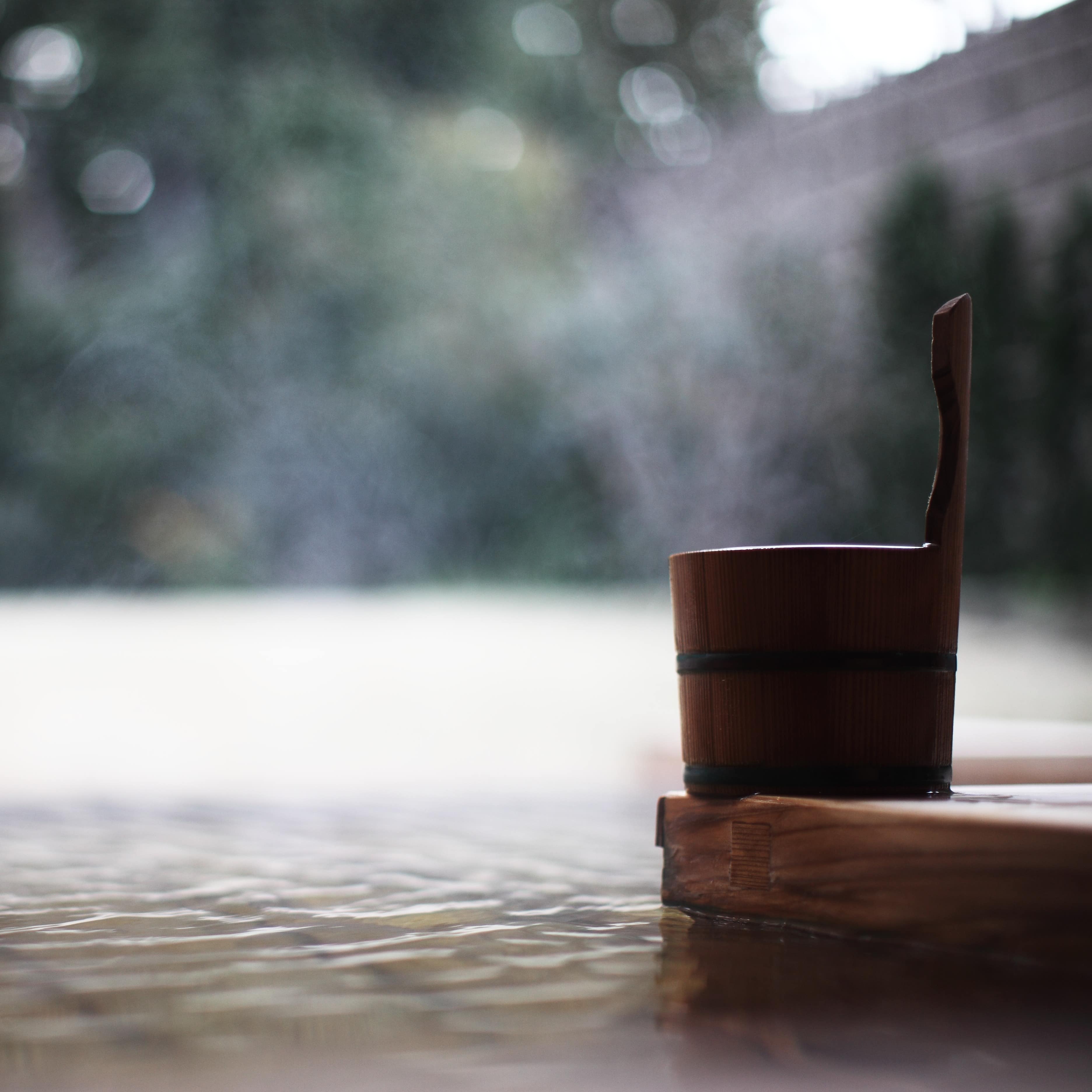Blurred water of a hot pool with a bucket in the foreground