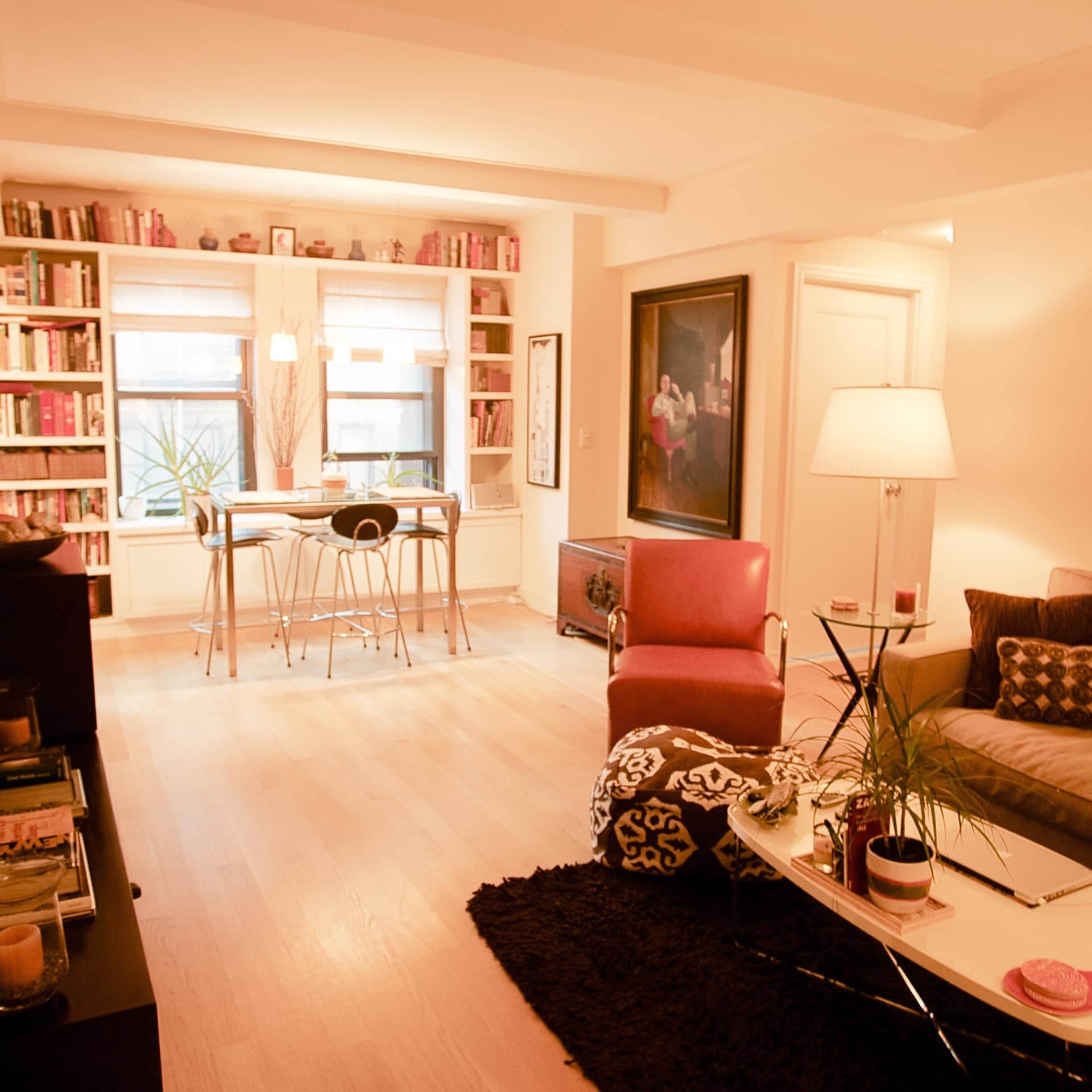Living room of Riverside Park apartment with green cloth sofa, red leather recliner, small dining table and a library