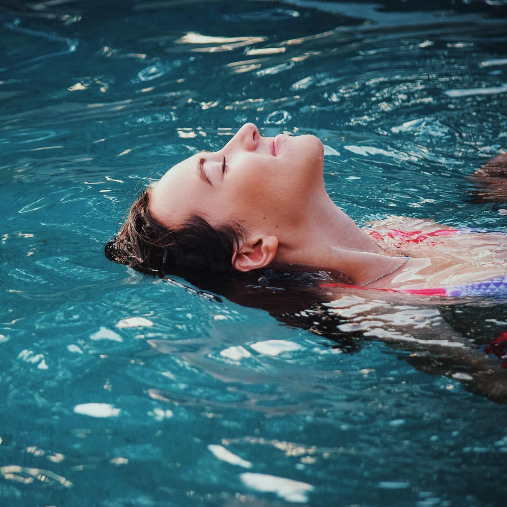 Woman relaxing in a pool with her head back in the water