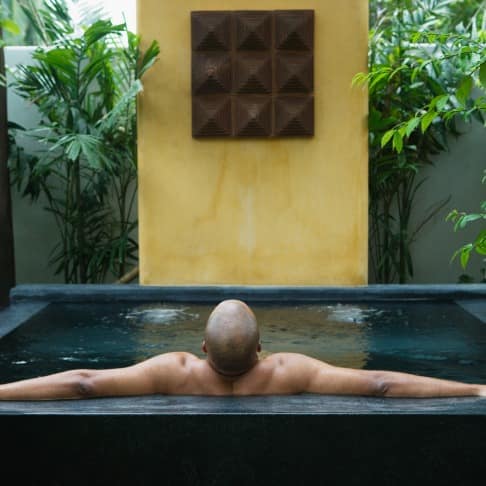 Man soaking in private pool surrounded by green trees and plants