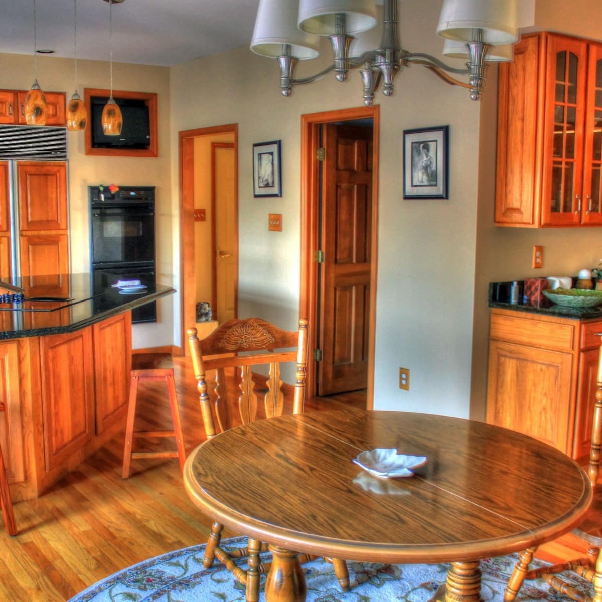 Kitchen and breakfast area of farmhouse with cherry cabinetry, oak floors, a breakfast bar and a round table